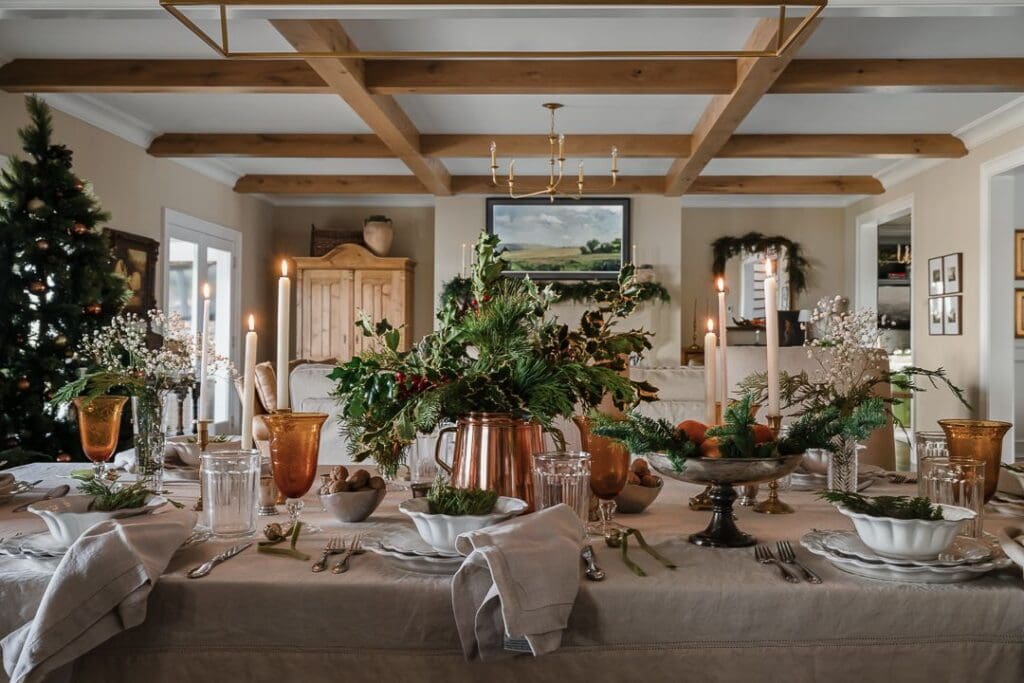 Close-up of the holiday tablescape: vintage brass candlesticks, amber glassware, and organic greenery create a collected mix of shine and softness.