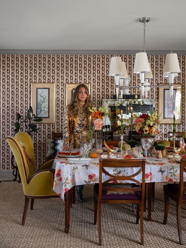 A richly layered fall dining room with vintage wallpaper, botanical wall art, and velvet wingback chairs, styled by interior designer Victoria Freise. Editorial interior photography captures this maximalist dining space, blending nostalgic charm with curated color and texture for a holiday-ready, designer home.