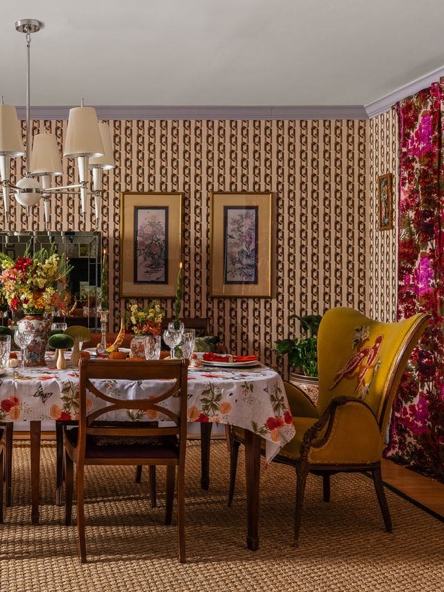 A richly layered fall dining room with vintage wallpaper, botanical wall art, and velvet wingback chairs, styled by interior designer Victoria Freise.Editorial interior photography captures this maximalist dining space, blending nostalgic charm with curated color and texture for a holiday-ready, designer home.