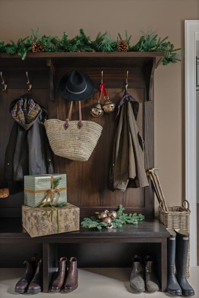 Mudroom with waxed jackets, riding boots, and seasonal packages, styled with understated holiday charm by Town & Country Design Studio and photographed to highlight texture and authenticity.